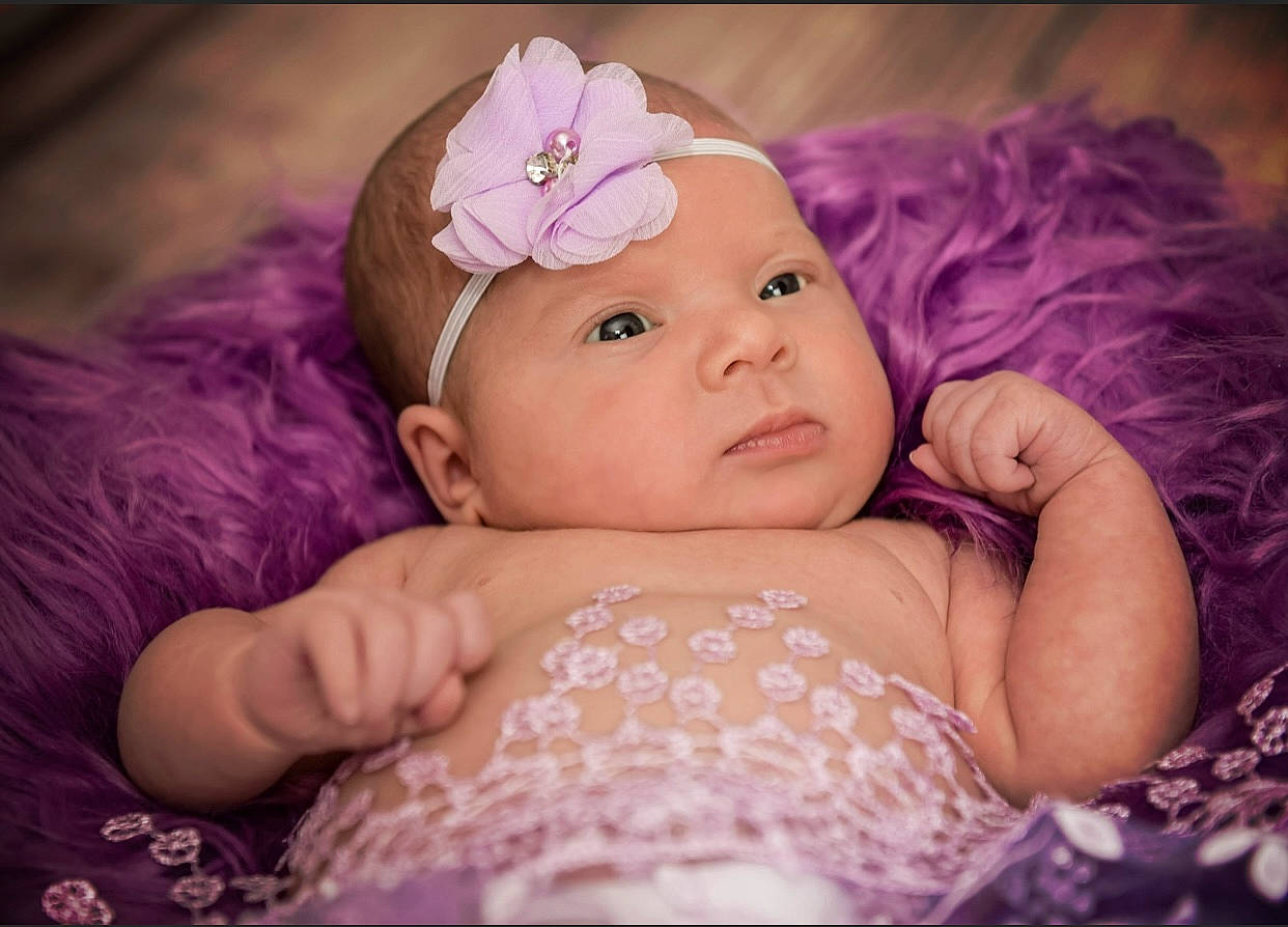 Camille is registered to the contest to win money with this photo: baby, baby_toddler_clothing, cap, dress, eye, flash_photography, grass, happy, headband, headpiece, headwear, human_body, iris, lip, person, petal, pink, purple, skin, toddler