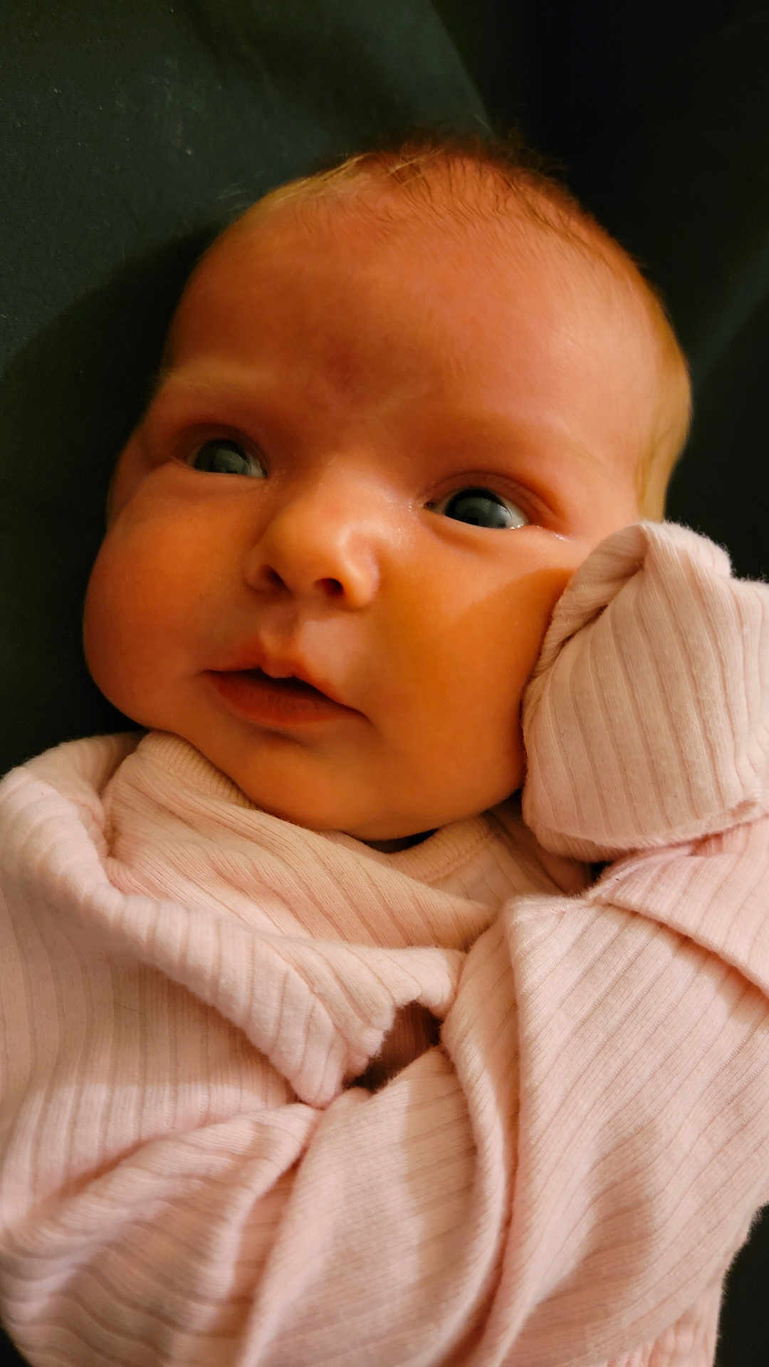 Phoebe is registered to the contest to win money with this photo: baby, infant, close_up, pink_clothing, cute, face, child, soft_texture, portrait, newborn, chubby_cheeks, looking_away, cozy, small_hands, sleepwear, indoors, skin, expression, young, adorable