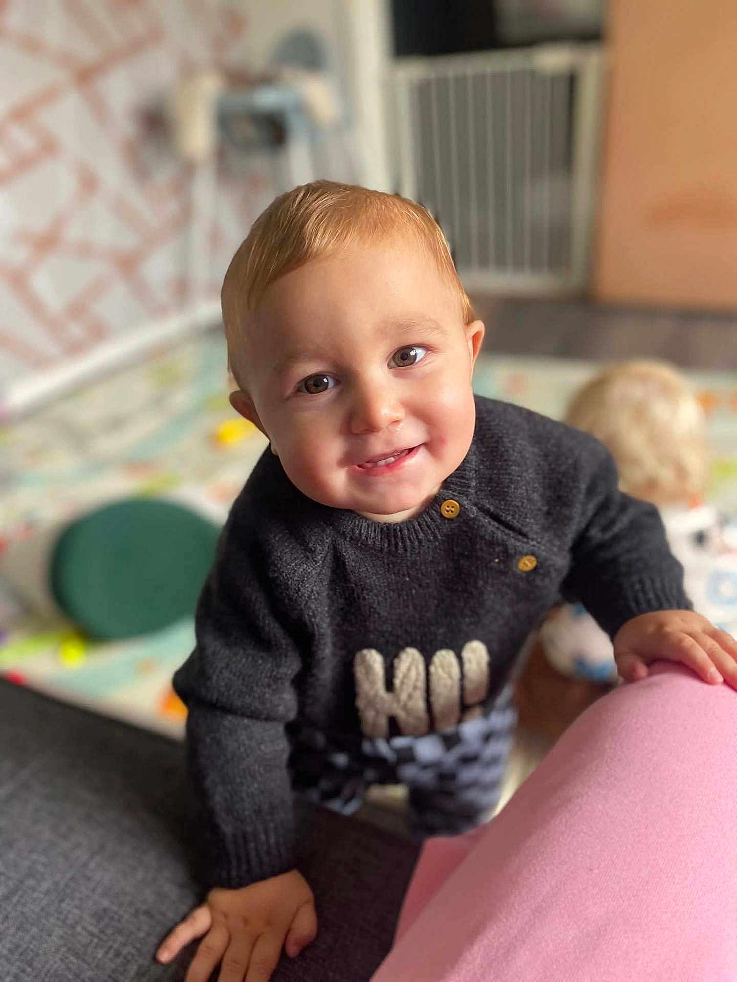 Hunter-James joined the competition — help win amazing prizes! toddler, child, smile, indoor, sweater, checkered_pants, hand, face, play, toy, baby_gate, floor, curiosity, background_blur, cozy, person, young_child, candid, expression, home