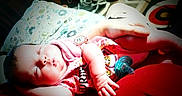 Maggie is registered to the contest to win money with this photo: baby, bed, child, close_up, cute, face, hands, home, indoor, infant, lying_down, nap, pacifier, peaceful, pillow, pink_clothing, portrait, red_blanket, sleeping, toy