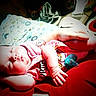 Maggie is registered to the contest to win money with this photo: baby, infant, sleeping, nap, portrait, face, child, red_blanket, pink_clothing, pacifier, toy, pillow, indoor, close_up, lying_down, peaceful, cute, hands, bed, home