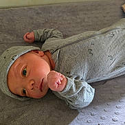 Declan is registered to the contest to win money with this photo: newborn, baby, infant, child, portrait, lying_down, blanket, gray, clothing, hat, bodysuit, fist, hands, eyes, face, indoors, soft_blanket, cozy, close_up, photography