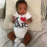Zayn joined the competition — help win amazing prizes! baby, infant, child, onesie, white_clothing, heart_symbol, cushion, blanket, sofa, socks, indoor, portrait, cute, seated, looking_at_camera, fabric_texture, skin, happy, small_hands, feet
