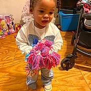 Legacy joined the competition — help win amazing prizes! child, girl, toy, yarn_doll, braids, pigtails, blue_bows, white_shirt, blue_pants, white_shoes, wooden_floor, toys, stroller, indoor, play, curious_expression, colorful, room, plastic_toys, floor