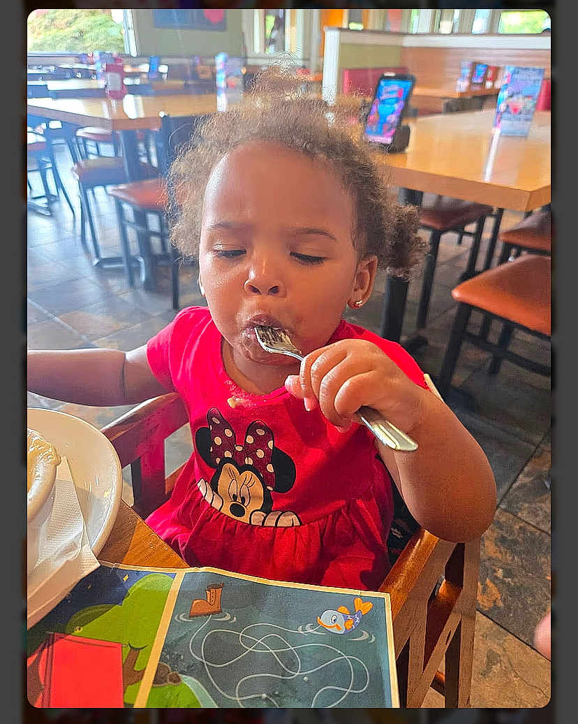 Legacy joined the competition — help win amazing prizes! child, toddler, girl, eating, fork, red_dress, minnie_mouse, restaurant, table, chair, high_chair, placemat, plate, activity_sheet, messy, curly_hair, earrings, indoor, concentration, family_dining