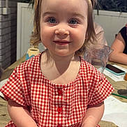 Malee is registered to the contest to win money with this photo: child, toddler, portrait, smile, blue_eyes, pigtails, red_checkered_dress, dress, handheld_device, barcode, wooden_table, indoor, houseplant, brick_wall, jug, smartphone, people, close_up, candid, dining