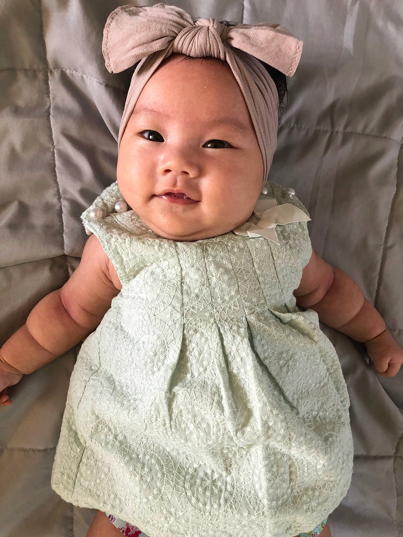 Ezri is registered to the contest to win money with this photo: baby, baby_products, beige, cheek, child, child_model, clothing, dress, ear, face, head, headgear, headwear, iris, outerwear, pattern, person, product, skin, smile