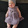 baby, smiling, knitted_hat, knitted_dress, knitted_booties, infant, happy, cute, sitting, indoors, couch, soft_fabric, plush, child, portrait, cute_expression, chubby_cheeks, handmade_clothing, cozy, comfortable