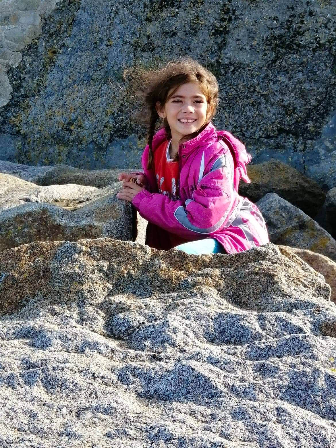 Kayhlia participe au concours pour gagner de l'argent avec cette photo : bedrock, body_of_water, formation, fun, geological_phenomenon, grass, happy, head, joy, landscape, leisure, outcrop, people_in_nature, person, recreation, rock, sitting, smile, soil, toddler