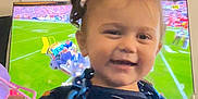 Valerie joined the competition — help win amazing prizes! blue_chain, child, cute, football_game, furniture, hair, hand, happy, indoor, living_room, pajamas, person, pigtails, playful, screen, smiling, sports_print, television, toddler, toy
