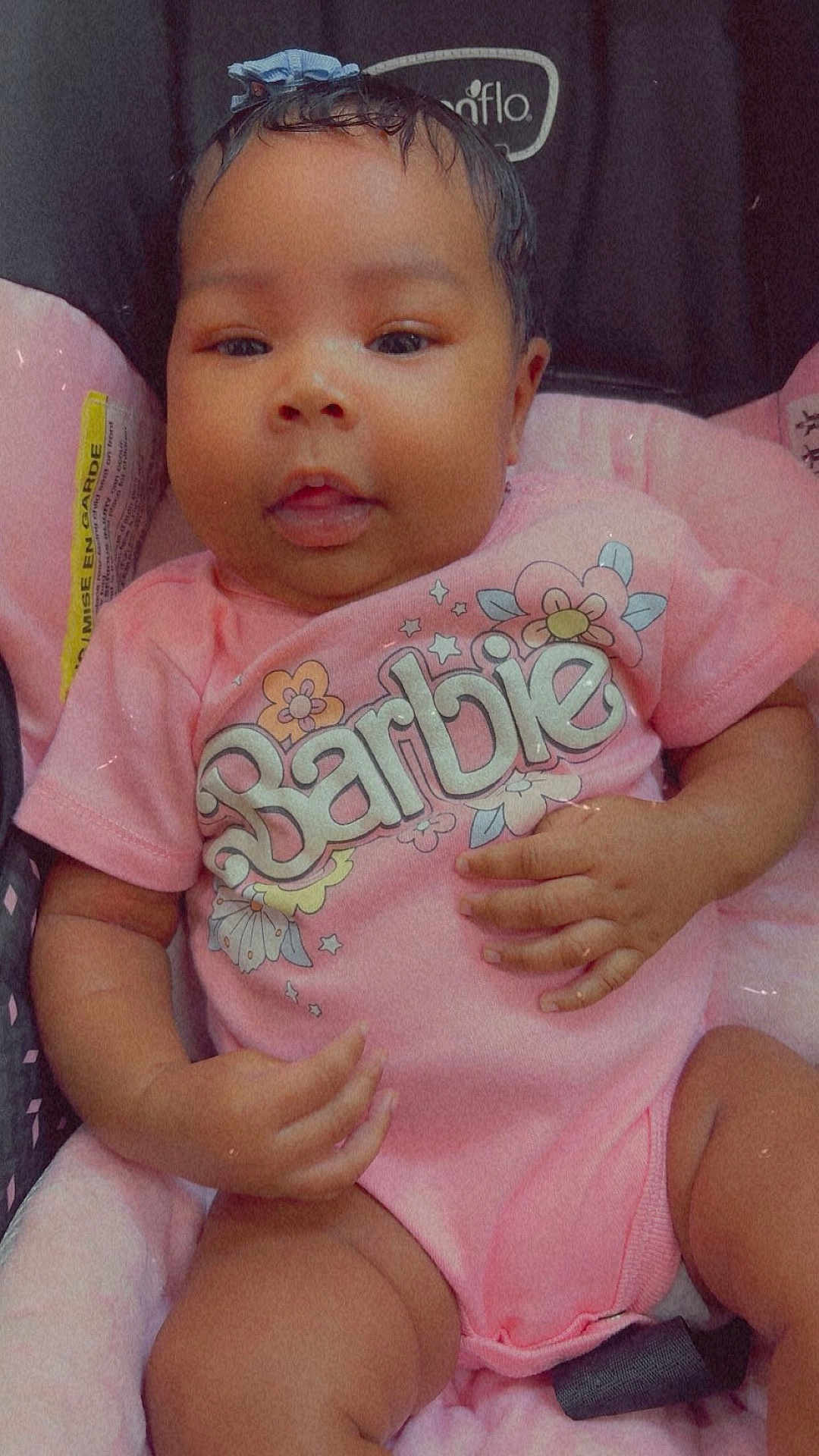 Cheris joined the competition — help win amazing prizes! baby, infant, car_seat, pink_clothing, onesie, bow, face, child, cute, chubby_cheeks, hand, legs, sitting, indoor, soft_toys, fabric, person, smiling, portrait, closeup