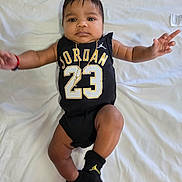 Eithan Zayas Medina is registered to the contest to win money with this photo: baby, child, infant, black_clothing, jordan, number_23, gold_chain, wristband, black_socks, blanket, white_blanket, lying_down, cute, face, arms_outstretched, indoors, portrait, expression, soft_lighting, person