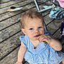 toddler, child, messy, blue_dress, striped_dress, wooden_deck, floor, barefoot, spoon, food_stains, face, hand, legs, chair, blanket, fabric, outdoor, playful, person, candid