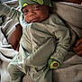 baby, infant, avocado_hat, pajamas, mittens, blanket, soft_texture, smile, sleepy, comfort, child, cute, cozy, hands, footwear, portrait, indoors, warm, relaxed, person