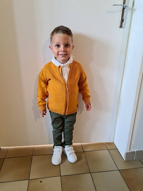 Tizio a rejoint le concours — aidez-le/la à gagner de superbes lots ! arm, baby_toddler_clothing, collar, dress_shirt, face, floor, flooring, gesture, happy, human_body, joint, joy, knee, leg, neck, person, sleeve, smile, standing, toddler