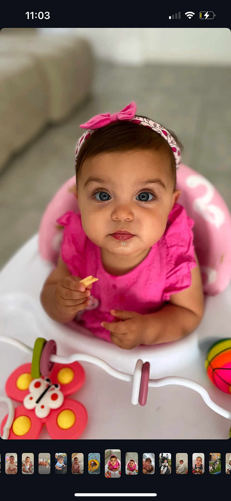 Leya a rejoint le concours — aidez-le/la à gagner de superbes lots ! baby, child, pink_clothing, headband, blue_eyes, highchair, toy, butterfly_toy, colorful_ball, snack, indoor, closeup, portrait, cute, infant, sitting, food, hand, face, curious