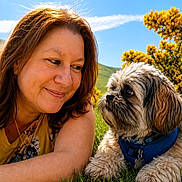 Chewy joined the competition — help win amazing prizes! woman, dog, grass, outdoor, blue_sky, flower, yellow_flower, pet, companion, nature, sunlight, portrait, happy, casual, relaxed, animal, friendship, daylight, smile, leisure