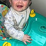 baby, child, walker, smile, happy, indoor, clothing, bib, face, hand, toy, colorful, yellow, blue, pattern, person, infant, cute, play, young