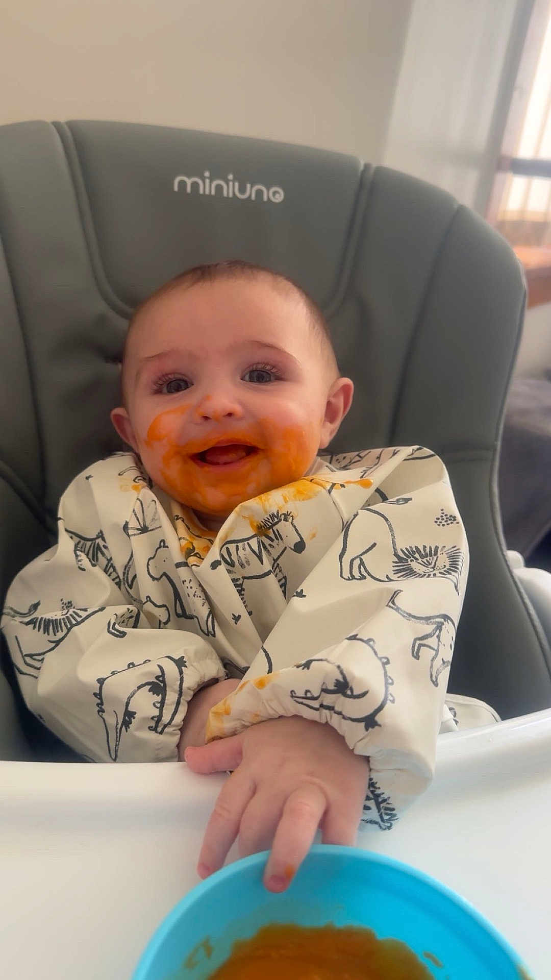 Cody joined the competition — help win amazing prizes! baby, high_chair, baby_food, bib, messy_face, smiling, hand, blue_bowl, feeding_time, indoor, cute, animal_print, child, happy, young_child, food, meal, infant, toddler, home