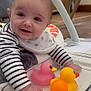 baby, child, rubber_duck, toy, smiling, indoor, floor, striped_clothing, bib, glass_container, furniture, wood_floor, playtime, infant, cute, happy, closeup, person, baby_toys, crawling