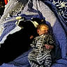 baby, newborn, sleeping, cat, black_and_white_cat, bed, blanket, pajamas, striped_clothing, animal, pet, cozy, resting, indoor, home, cute, peaceful, together, infant, soft_lighting