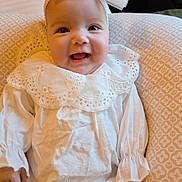 Milena a rejoint le concours — aidez-le/la à gagner de superbes lots ! baby, infant, smile, white_clothing, bow, headband, lace, cushion, pattern, cute, portrait, happy, child, indoors, soft_lighting, sitting, closeup, face, small_hands, cozy