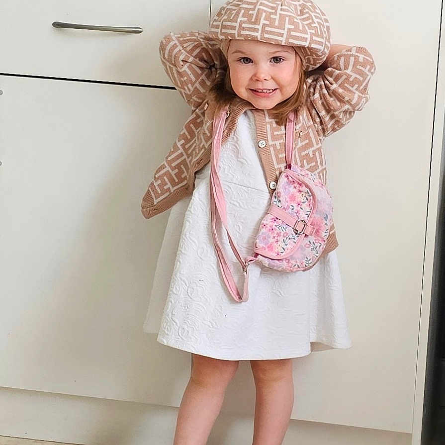 Elena participe au concours pour gagner de l'argent avec cette photo : beret, cabinet, cardigan, child, cute, fashion, floor, girl, happy, indoor, kitchen, patterned, person, pink, portrait, purse, sandals, smile, standing, white_dress