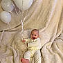baby, balloons, blanket, smile, happy, child, cozy, indoors, cream_color, ribbed_clothing, barefoot, sitting, celebration, cute, infant, soft_texture, joyful, playful, fabric, portrait