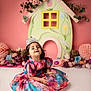 toddler, child, girl, dress, tiara, flower, floral_dress, smiling, sitting, indoor, portrait, colorful, cute, happy, decor, pink_background, playful, young_child, innocence, celebration