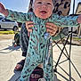 Logan is registered to the contest to win money with this photo: baby, child, smiling, onesie, outdoor, sunny, pacifier, person, hands, feet, car, hose, concrete, shadow, chair, clothing, headwear, happy, support, nature