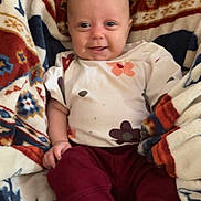 Adaline joined the competition — help win amazing prizes! apparel, baby, blanket, child, cozy, cute, face, feet, floral_shirt, hands, happy, indoor, infant, maroon_pants, patterned_blanket, portrait, sitting, smiling, soft_texture, young_child