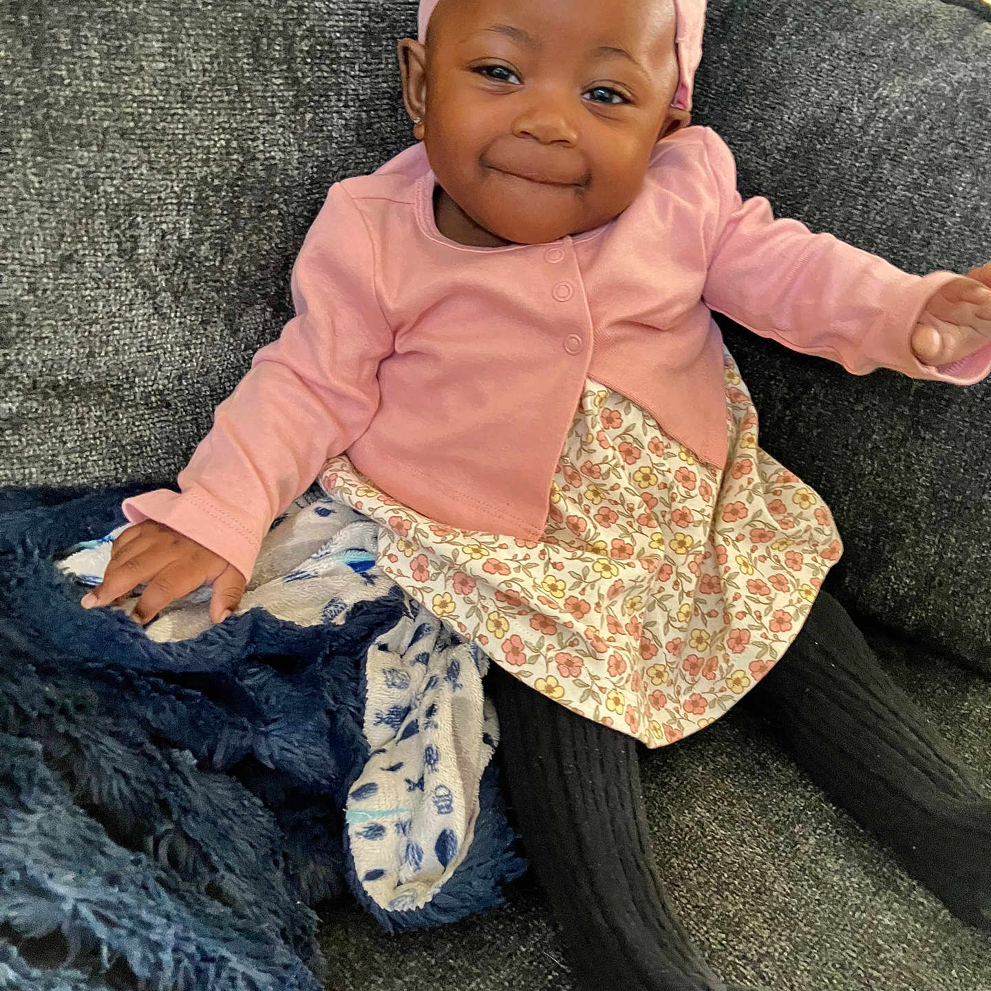 Blessing joined the competition — help win amazing prizes! baby, black_tights, blanket, child, couch, cozy, cute, floral_dress, girl, happy, home, indoors, infant, pink_cardigan, pink_headband, portrait, seated, smile, soft_fabric, toddler