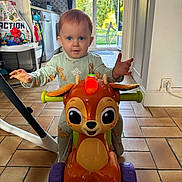 Jöy participe au concours pour gagner de l'argent avec cette photo : toddler, child, toy, indoor, floor, pajamas, deer_toy, wheels, kitchen, doorway, garden, window, tile_floor, play, cute, happy, person, furniture, light, expression