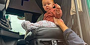 Jöy a rejoint le concours — aidez-le/la à gagner de superbes lots ! baby, child, red_hair, truck_interior, steering_wheel, seat, hand, curtain, window, vehicle, clothing, person, floor_mat, dashboard, adult_hand, indoors, car_seat, blanket, curtains, blue_eyes