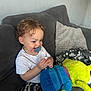 Ronnie joined the competition — help win amazing prizes! blanket, child, childhood, couch, cozy, curly_hair, cushion, happy, home, indoor, pacifier, person, playful, plush_toy, sitting, smiling, striped_pants, toddler, toy, white_tshirt
