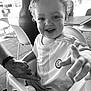 adult_hand, baby, black_and_white, cafe, chair, chelsea_football_club, child, close_up, curly_hair, hand_holding, happy, high_chair, jersey, outdoor, person, playful, portrait, smiling, table, toddler