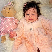 Izzy is registered to the contest to win money with this photo: baby, child, infant, plush_doll, toy, pink, polka_dot, soft_blanket, fur_coat, cute, indoor, portrait, expression, fussy, hand, hair_clip, fabric, comfort, lying_down, cozy