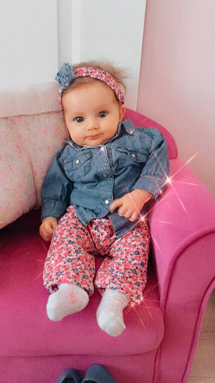 Noëlia a rejoint le concours — aidez-le/la à gagner de superbes lots ! baby, baby_toddler_clothing, cheek, child, child_model, doll, hair_accessory, headband, pattern, person, pink, sitting, skin, sleeve, toddler, toy