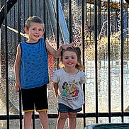 Ryder is registered to the contest to win money with this photo: child, children, boy, girl, water_fountain, summer_clothing, smile, outdoor, playful, sunlight, fence, shorts, tshirt, happy, portrait, nature, daytime, casual, park, friends