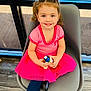 child, girl, smiling, pink_dress, toy, chair, indoor, window, floor, happy, person, sitting, cute, playful, young, casual_clothing, long_hair, bright, portrait, fashion