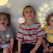 Tannen joined the competition — help win amazing prizes! child, kids, sitting, indoor, wall, sparkle_effect, yellow_shirt, striped_shirt, gray_shirt, shorts, barefoot, playful, cute, portrait, three_children, magic, light, background, happy, expression