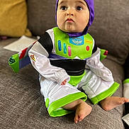 Yamari joined the competition — help win amazing prizes! baby, child, costume, buzz_lightyear, purple_hood, green, white, couch, indoor, foot, sitting, curious, face, cute, clothing, pants, long_sleeve, toy_story, person, infant