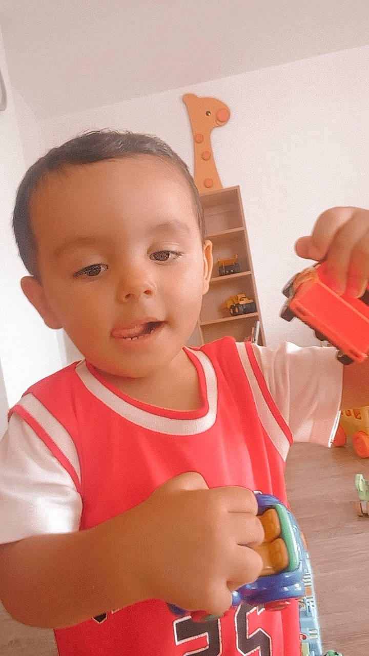 Mathys participe au concours pour gagner de l'argent avec cette photo : arm, baby, baby_playing_with_toys, baby_products, baby_toddler_clothing, child, finger, fun, happy, nail, neck, person, play, room, sitting, smile, t_shirt, thumb, toddler, vacation