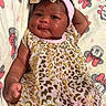 baby, infant, child, portrait, lying_down, smiling, face, eyes, headband, bow, dress, leopard_print, pink_clothing, blanket, plush_blanket, cartoon_pattern, indoor, close_up, adorable, photography