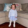 toddler, child, girl, indoor, living_room, sofa, cushion, plush_toy, bunny, clothing, dress, tights, shoes, wooden_floor, furniture, portrait, cute, standing, person, home
