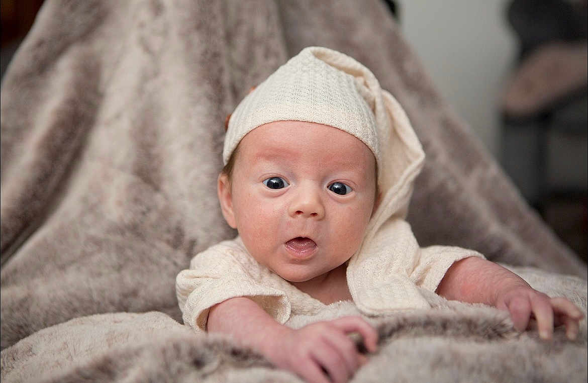 Amari joined the competition — help win amazing prizes! baby, infant, hat, blanket, knitwear, cozy, soft_texture, portrait, wide_eyes, curious, expression, skin, hands, lying_down, indoors, cute, child, newborn, warm, comfort