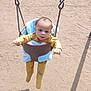 baby, swing, playground, sand, child, yellow_pajamas, outdoor, sunlight, shadow, curious, infant, seat, blue_blanket, metal_chains, toy, play, person, casual_clothing, daytime, park
