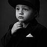 Marcelino joined the competition — help win amazing prizes! child, portrait, black_and_white, baseball_cap, formal_suit, blazer, pocket_square, hand, thoughtful, serious, face, eyes, indoors, studio, dramatic_lighting, monochrome, fashion, young, standing, photography