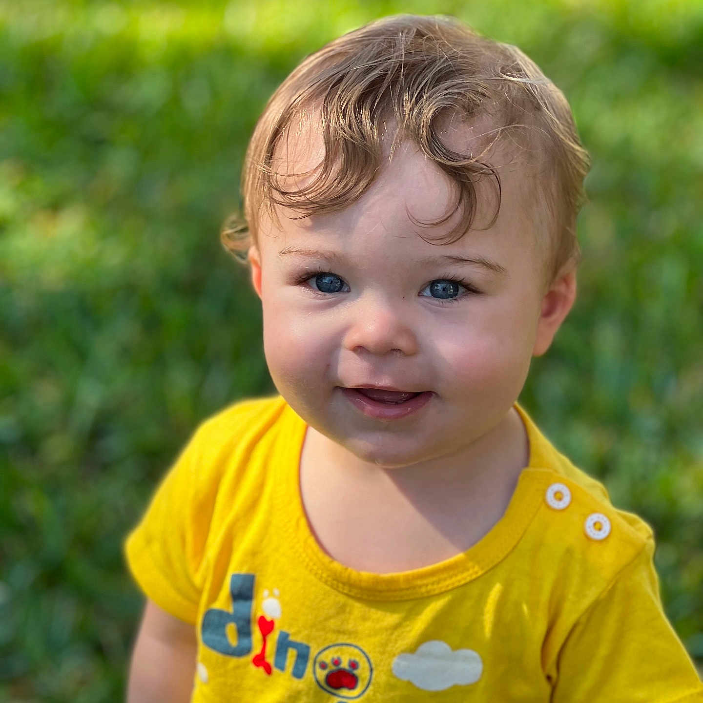 Grayson joined the competition — help win amazing prizes! baby, blonde, bodypart, clothing, face, frown, grass, hair, happy, head, lawn, mouth, person, photography, plant, portrait, shirt, smile, t_shirt, teeth