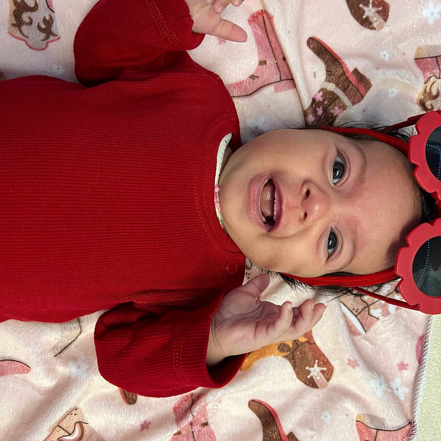 Eva Cecília joined the competition — help win amazing prizes! baby, blanket, child, cowboy_boots, cute, face, hand, happy, headband, indoor, infant, lying_down, pattern, person, portrait, red_clothing, smile, star_pattern, sunglasses, teeth